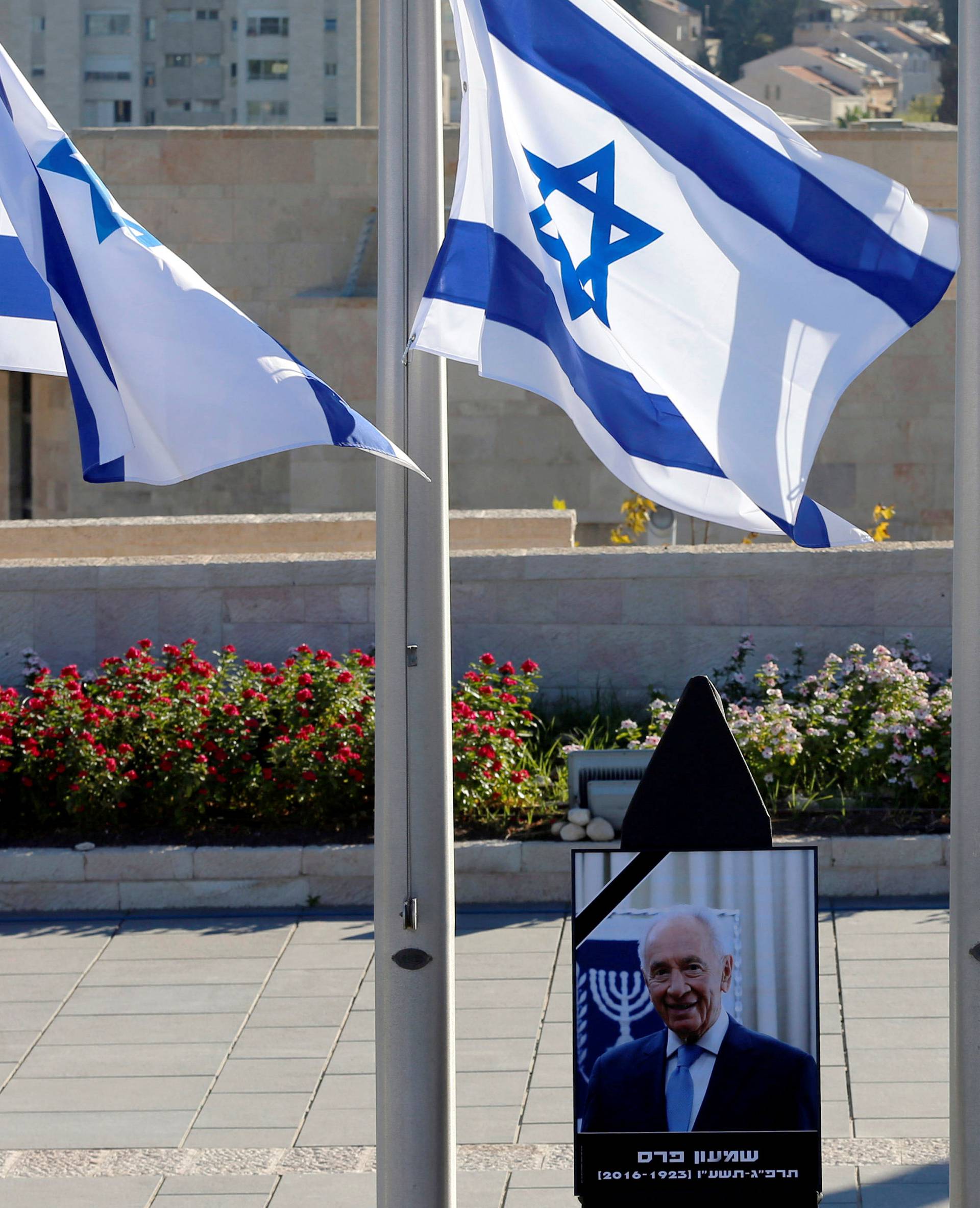A portrait of former Israeli President Shimon Peres is seen near Israeli flags lowered to half mast at the Knesset plaza, the Israeli parliament, ahead of his funeral, in Jerusalem 