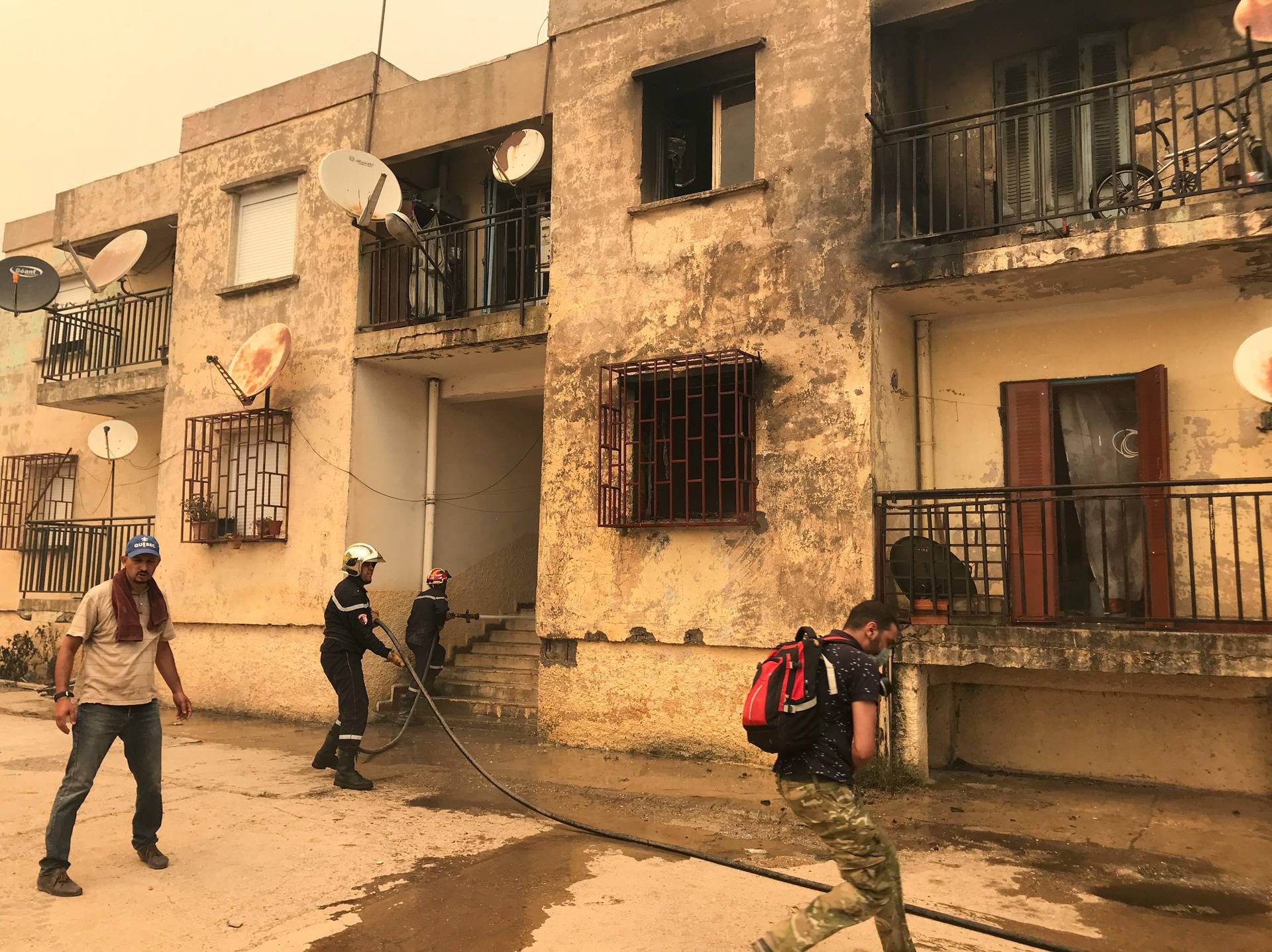 Firefighters and residents attempt to put out a fire at a building in Ain al-Hammam village