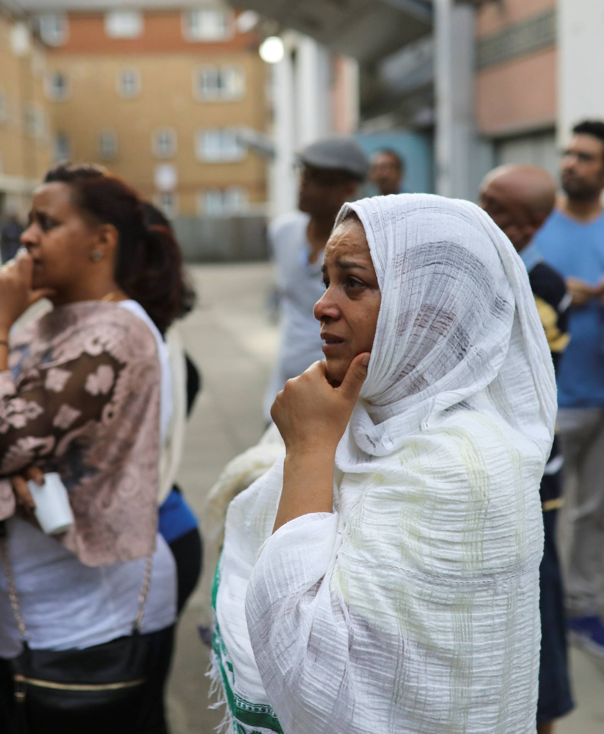 Women react as they look at the Grenfell apartment tower block in North Kensington, London