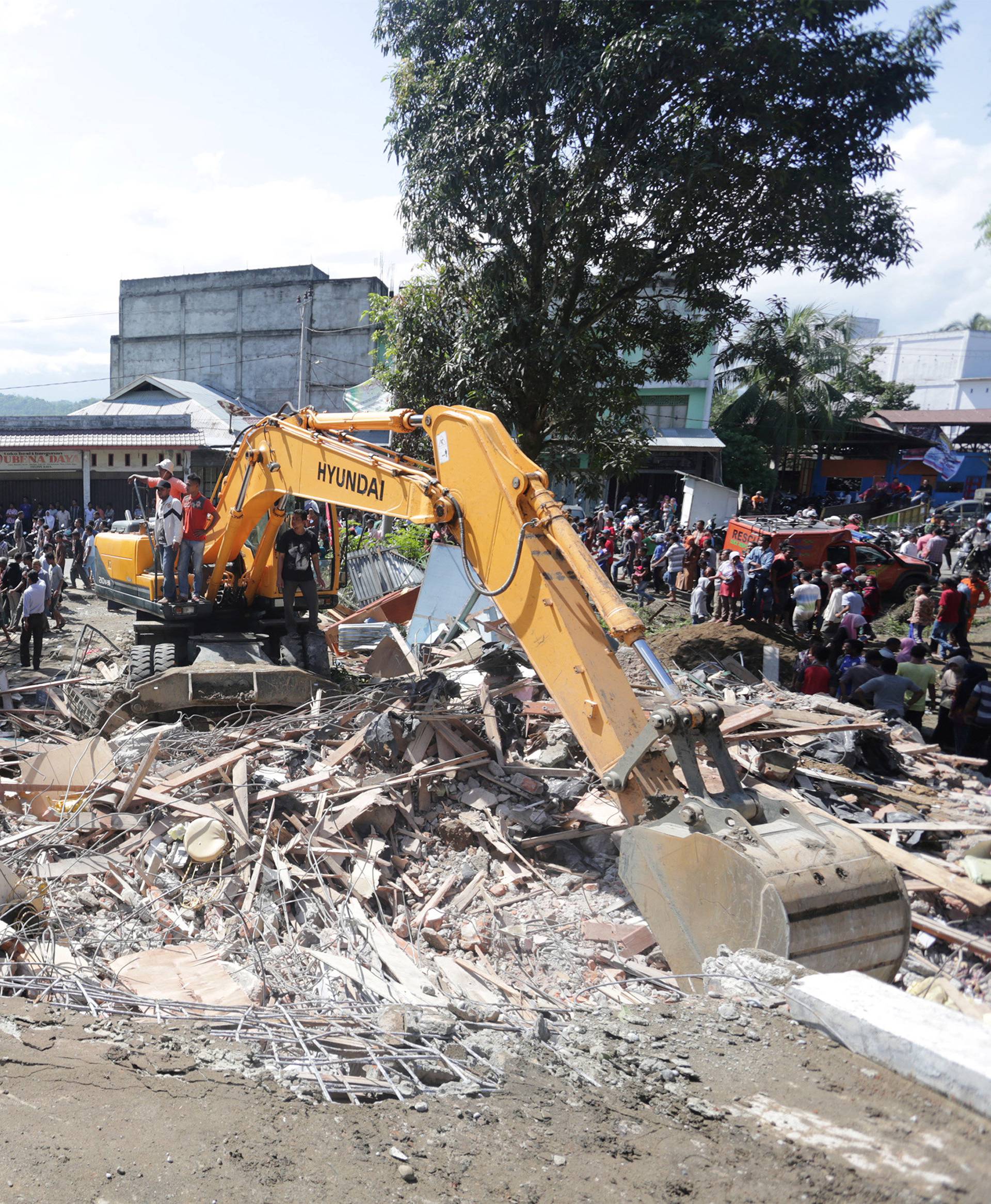 Rescue workers use heavy equipment to search for victims in a collapsed building following an earthquake in Lueng Putu, Pidie Jaya in the northern province of Aceh