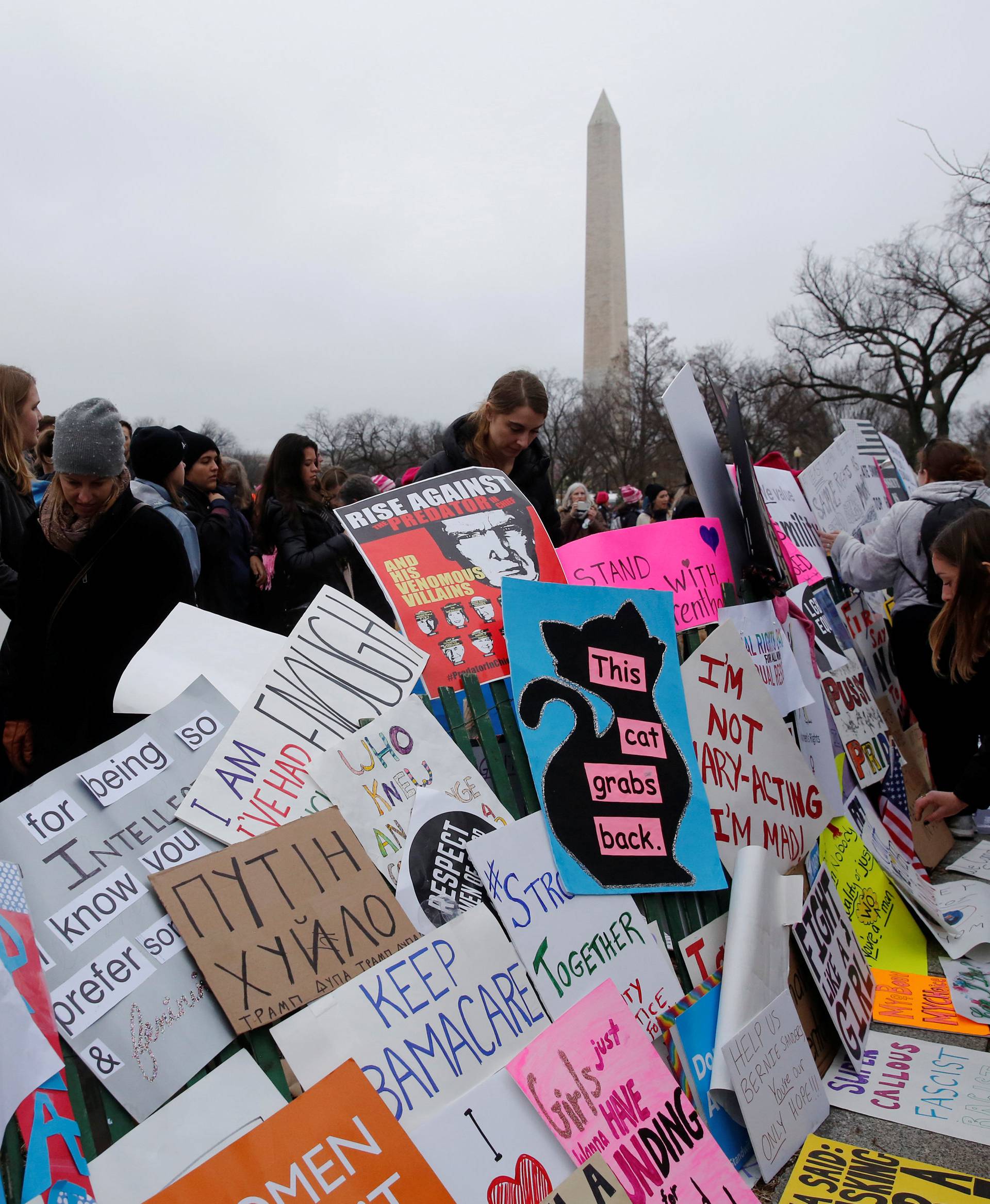 Protesters in the Women's March attach their signs to a fence near the White House in Washington