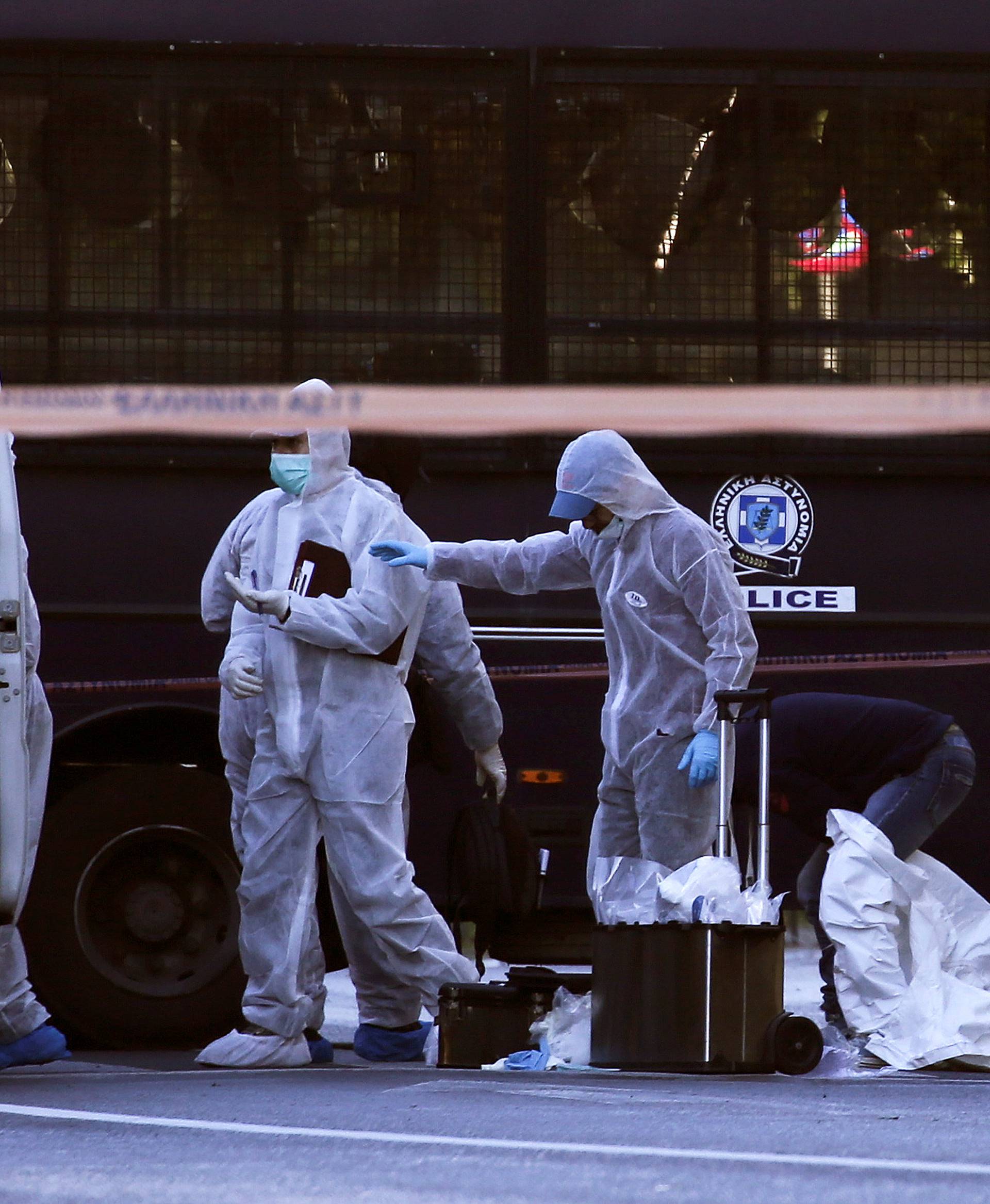 Forensics experts search for evidence outside the French Embassy, where unidentified attackers threw an explosive device which caused a small blast, in Athens