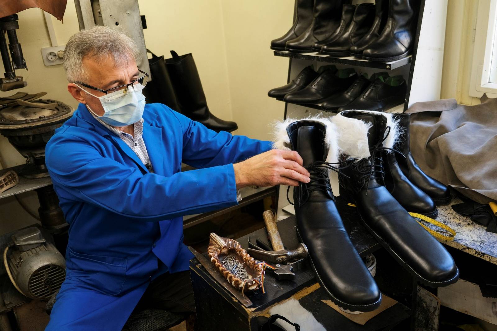 Romanian cobbler Grigore Lup presents a pair of oversized winter boots after finishing them