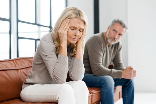 Frustrated senior couple at home, sitting on the couch and keep silent in a quarrel