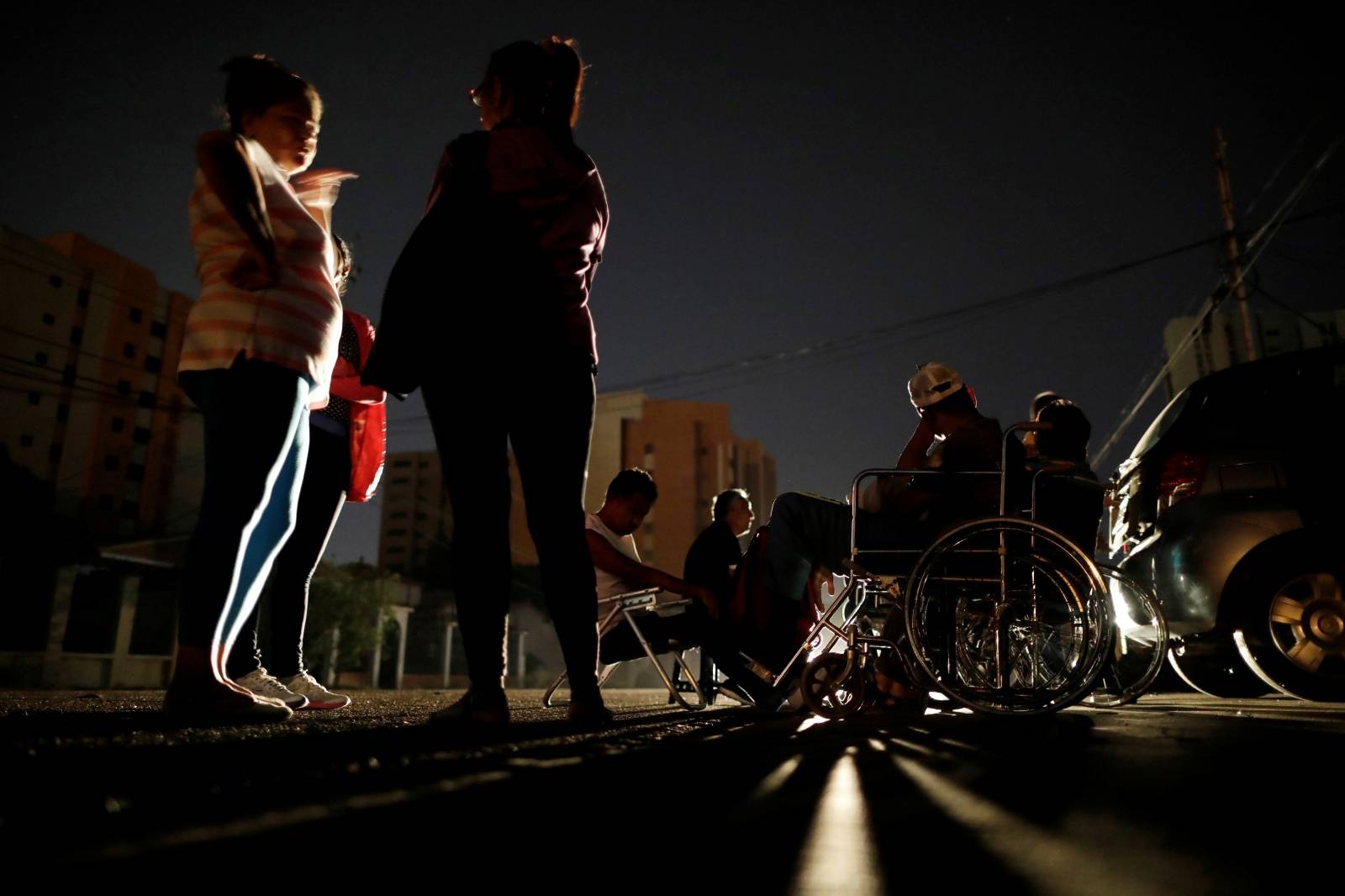 Patients with kidney disease and their relatives wait on the street for the return of electricity, in front of a dialysis center, during a blackout in Maracaibo