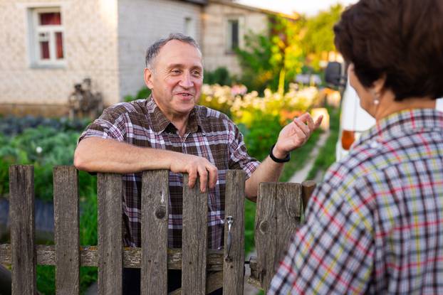 Neighbors,Middle,Aged,Man,And,Woman,Chatting,Near,The,Fence