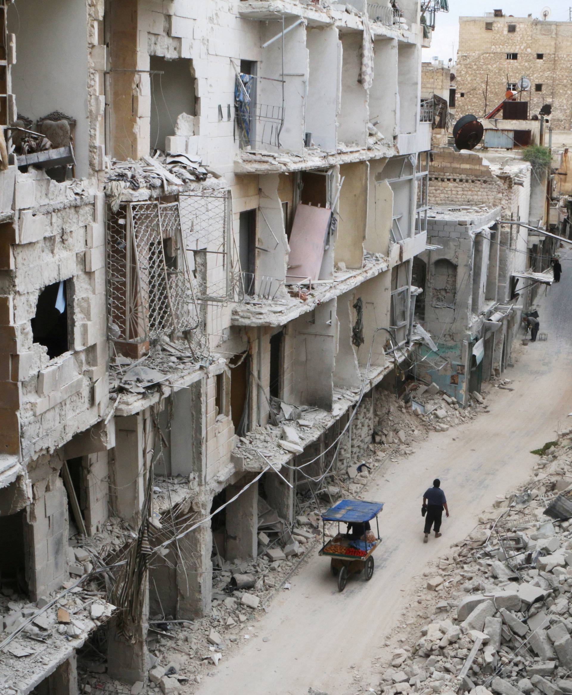 Residents walk near damaged buildings in the rebel held area of Old Aleppo