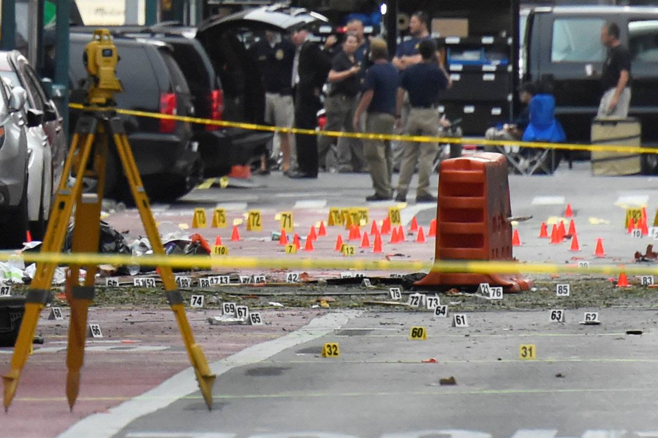 Evidence markers on the street surround security officials near site of explosion in New York