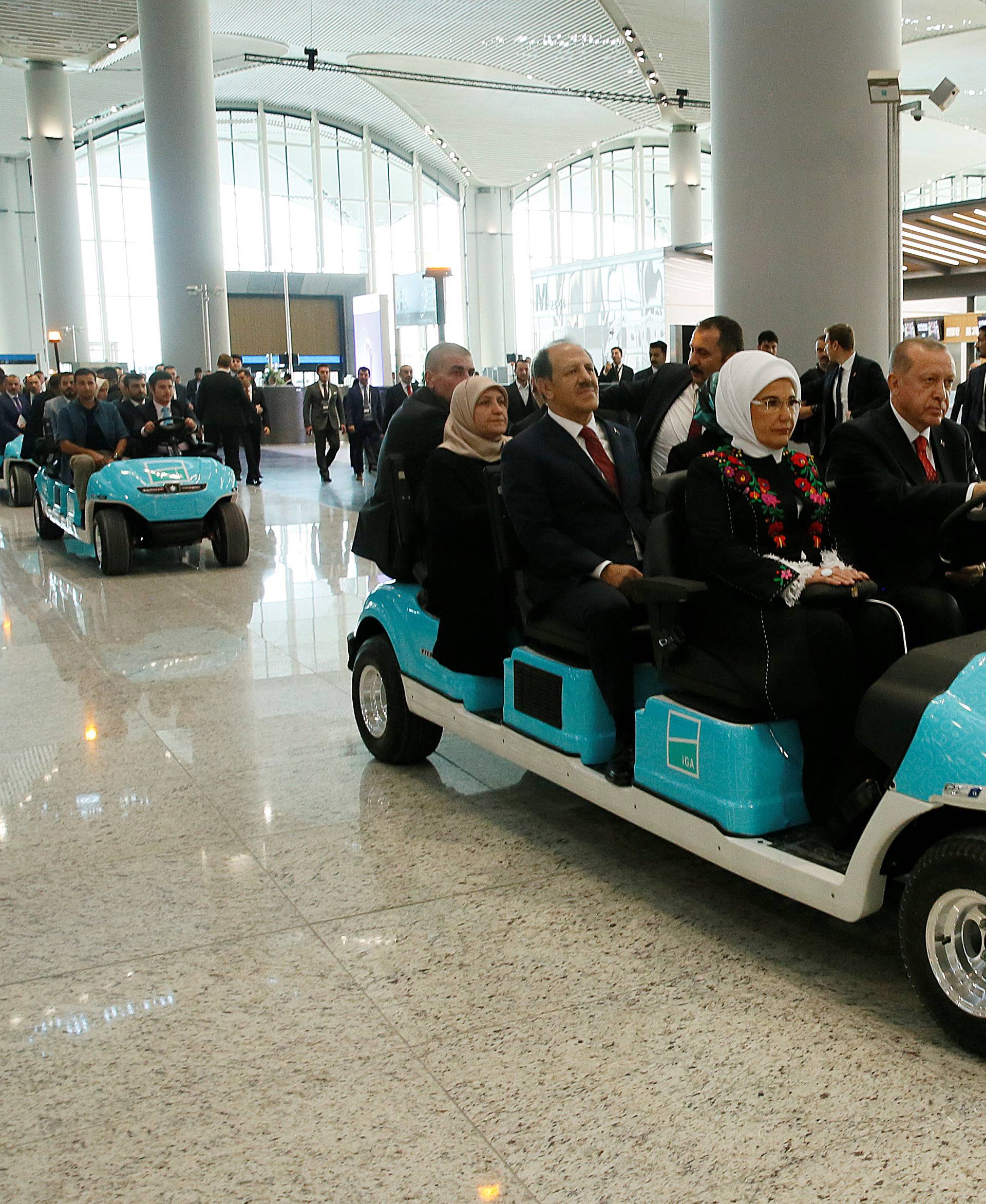 Turkey's President Tayyip Erdogan drives an airport golf cart as he is flanked by his wife Emine Erdogan and officials during the official opening ceremony of Istanbul's new airport in Istanbul