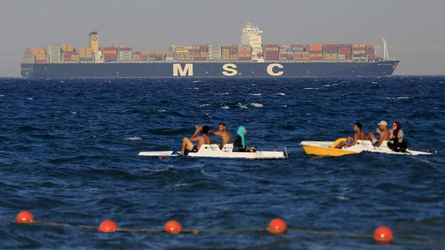 FILE PHOTO: People enjoy the water as a container ship crosses the Gulf of Suez towards the Red Sea before entering the Suez Canal, in El Ain El Sokhna in Suez, east of Cairo, Egypt