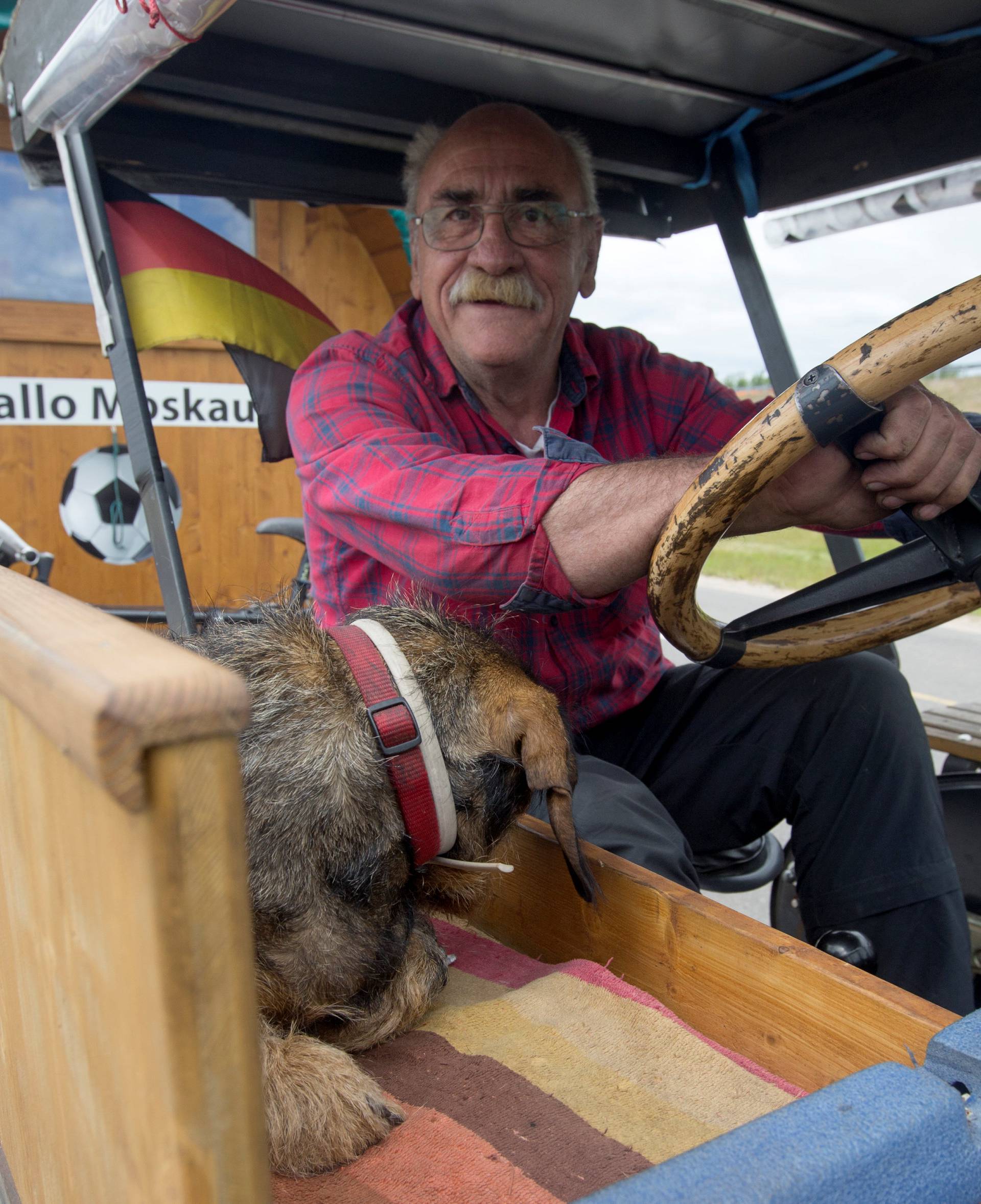 Soccer fan from Pforzheim, Germany, Hubert Wirth, 70, with his dog Hexe, drives his tractor with a trailer to attend the FIFA 2018 World Cup in Russia near the village of Yasen