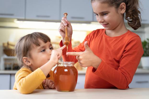 Happy,Children,Eating,Honey,From,A,Jar,At,Home,In
