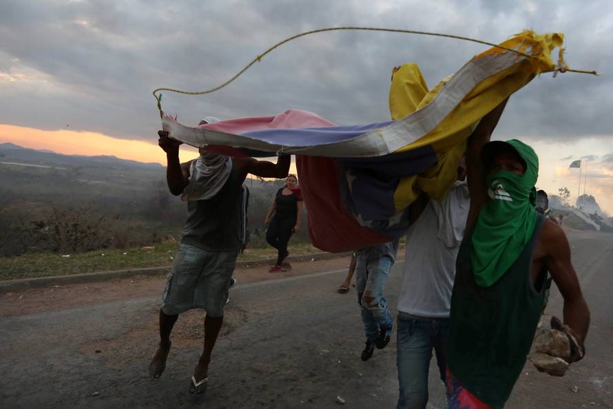 People hold Venezuela's national flag at the border between Venezuela and Brazil in Pacaraima