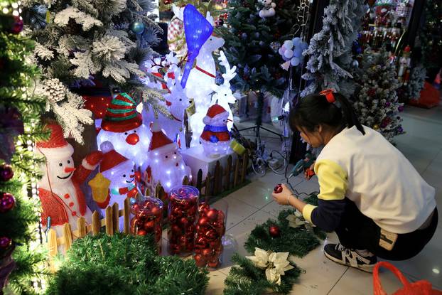 FILE PHOTO: A staff member assembles a Christmas decoration at a booth in a mall in Beijing