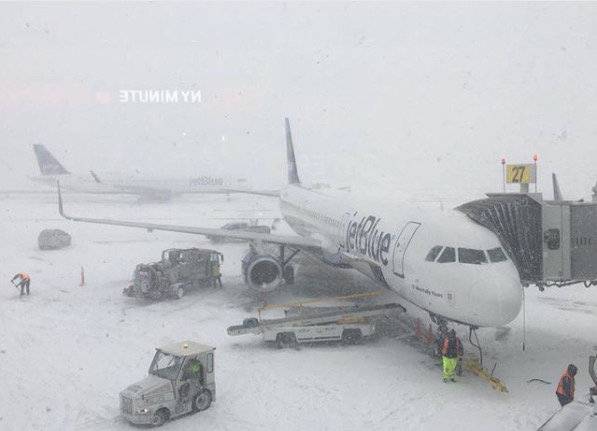 Staff work on next to a parked plane at John F. Kennedy International Airport during a snow storm, in Queens, New York