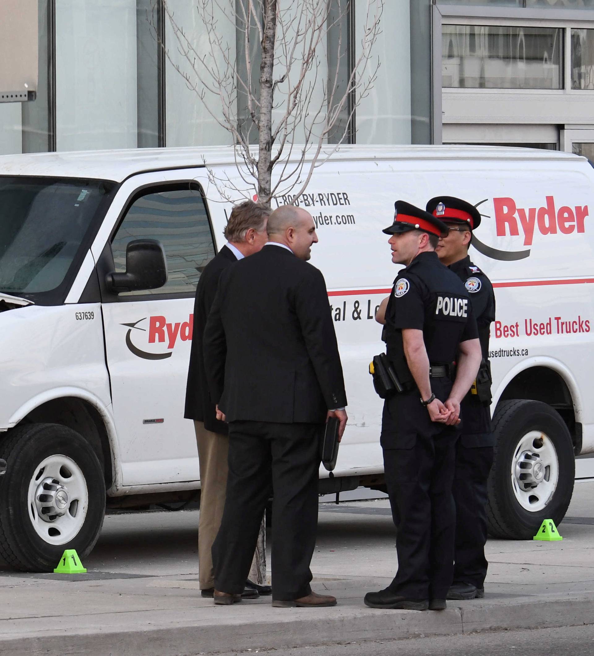 Investigators view a damaged van seized by police after multiple people were struck at a major intersection northern Toronto