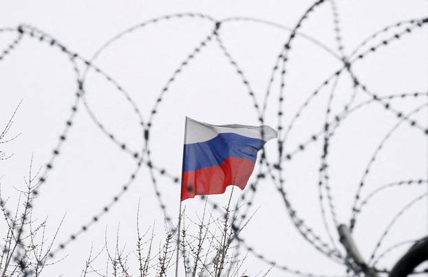 FILE PHOTO: The Russian flag is seen through barbed wire as it flies on the roof of the Russian embassy in Kiev