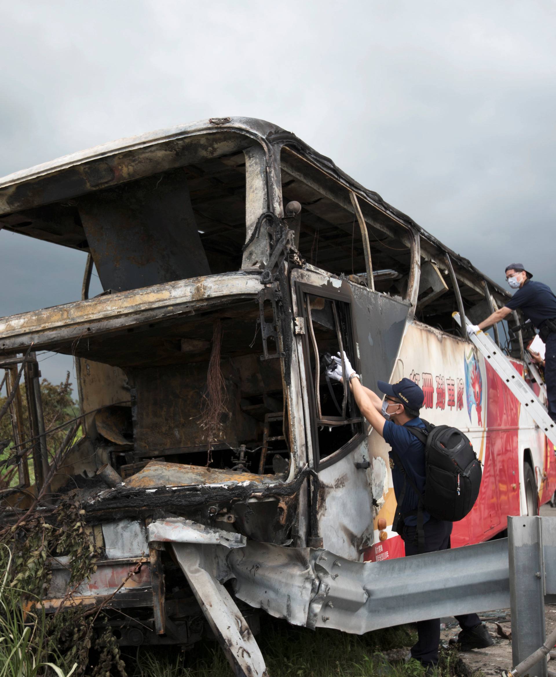 Police and other emergency personnel work around the wreckage of a bus that crashed en route to Taoyuan airport, just south of the capital Taipei