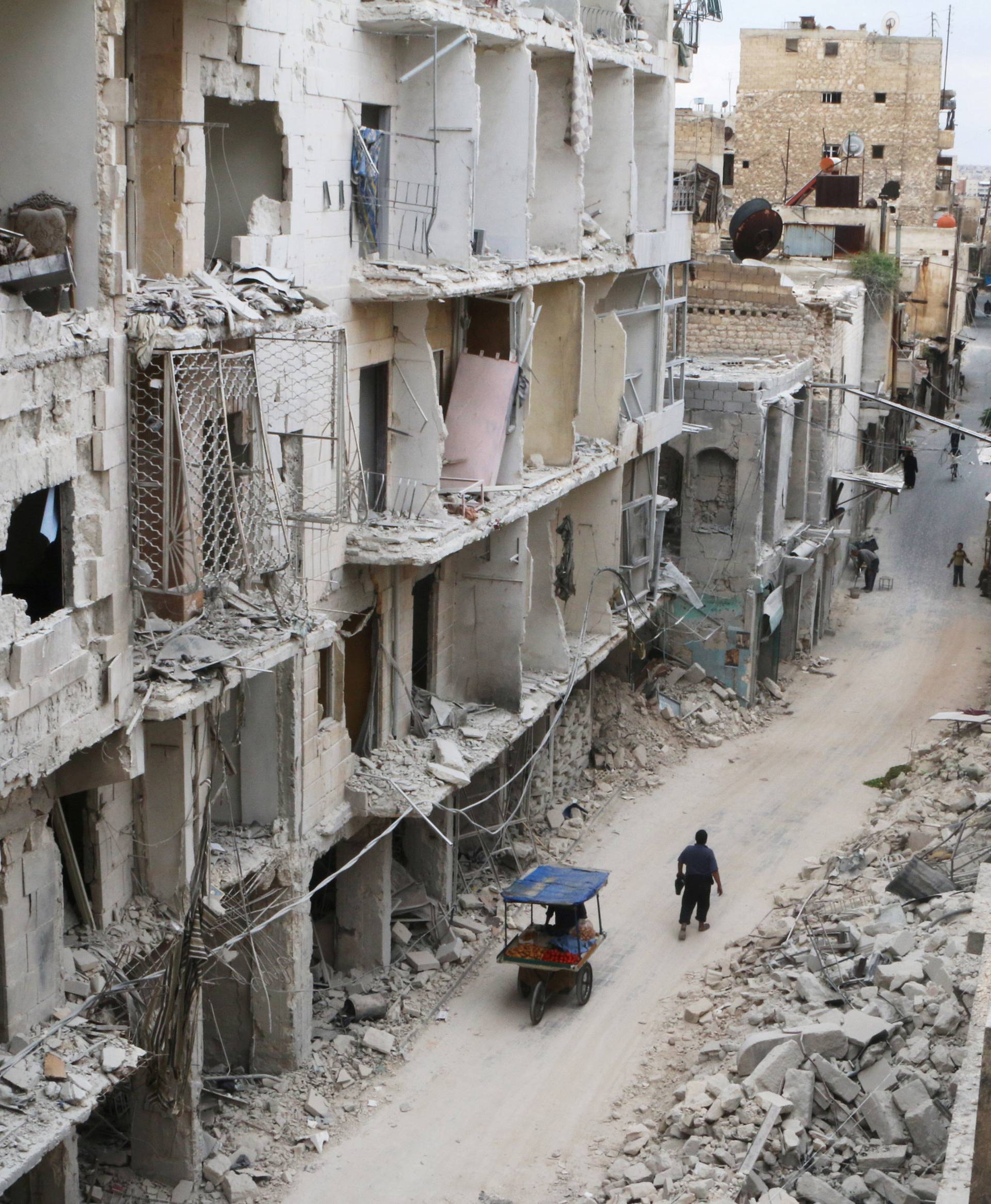 Residents walk near damaged buildings in the rebel held area of Old Aleppo