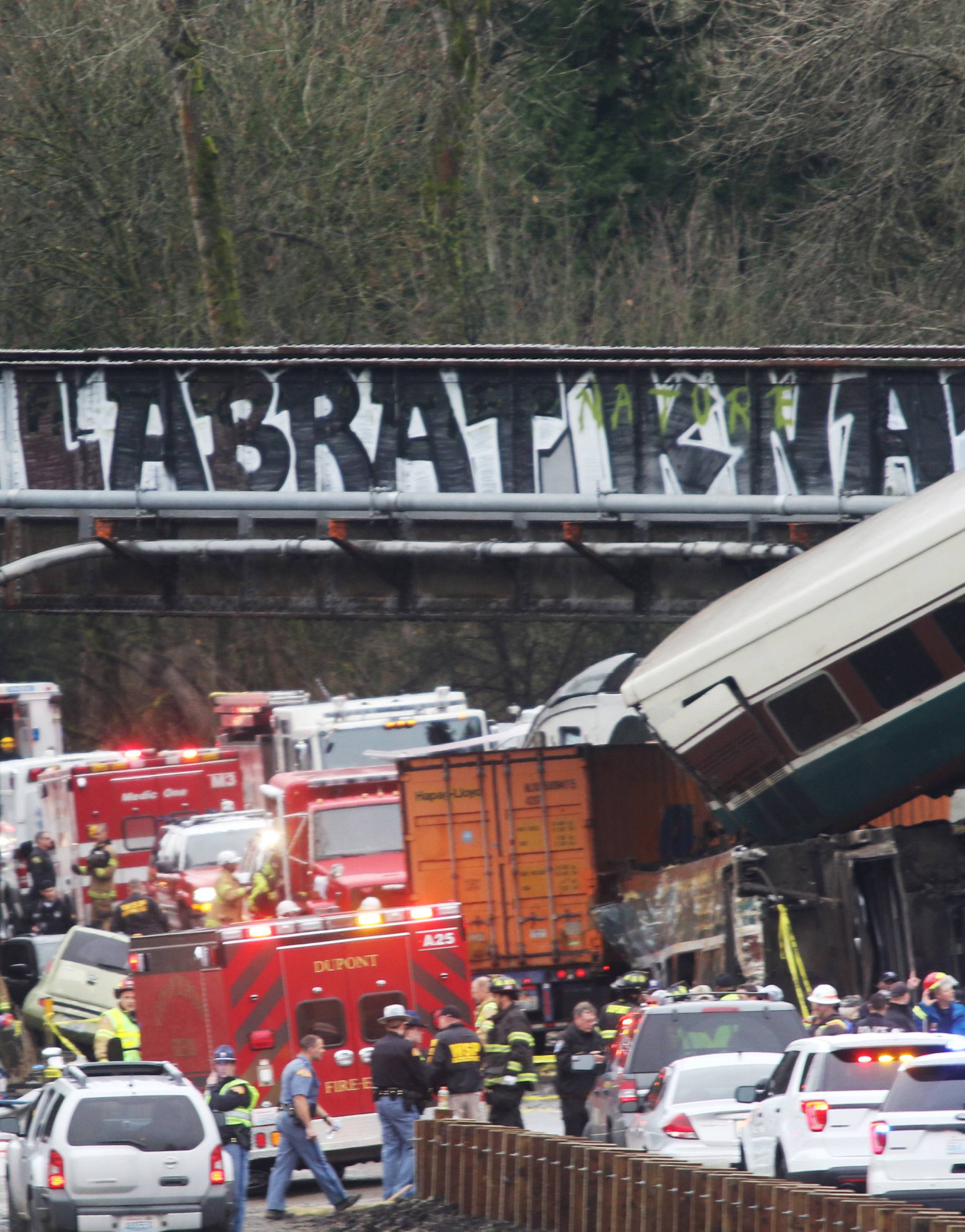 First responders are seen at the scene of an Amtrak passenger train which derailed and is hanging from a bridge over the I-5 in DuPont