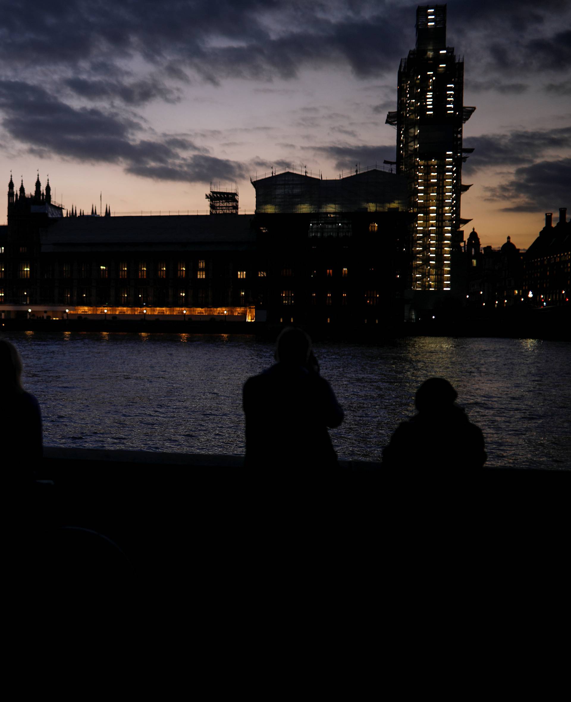 People enjoy the view on the south bank of the River Thames, opposite the Houses of Parliament, in Westminster, central London