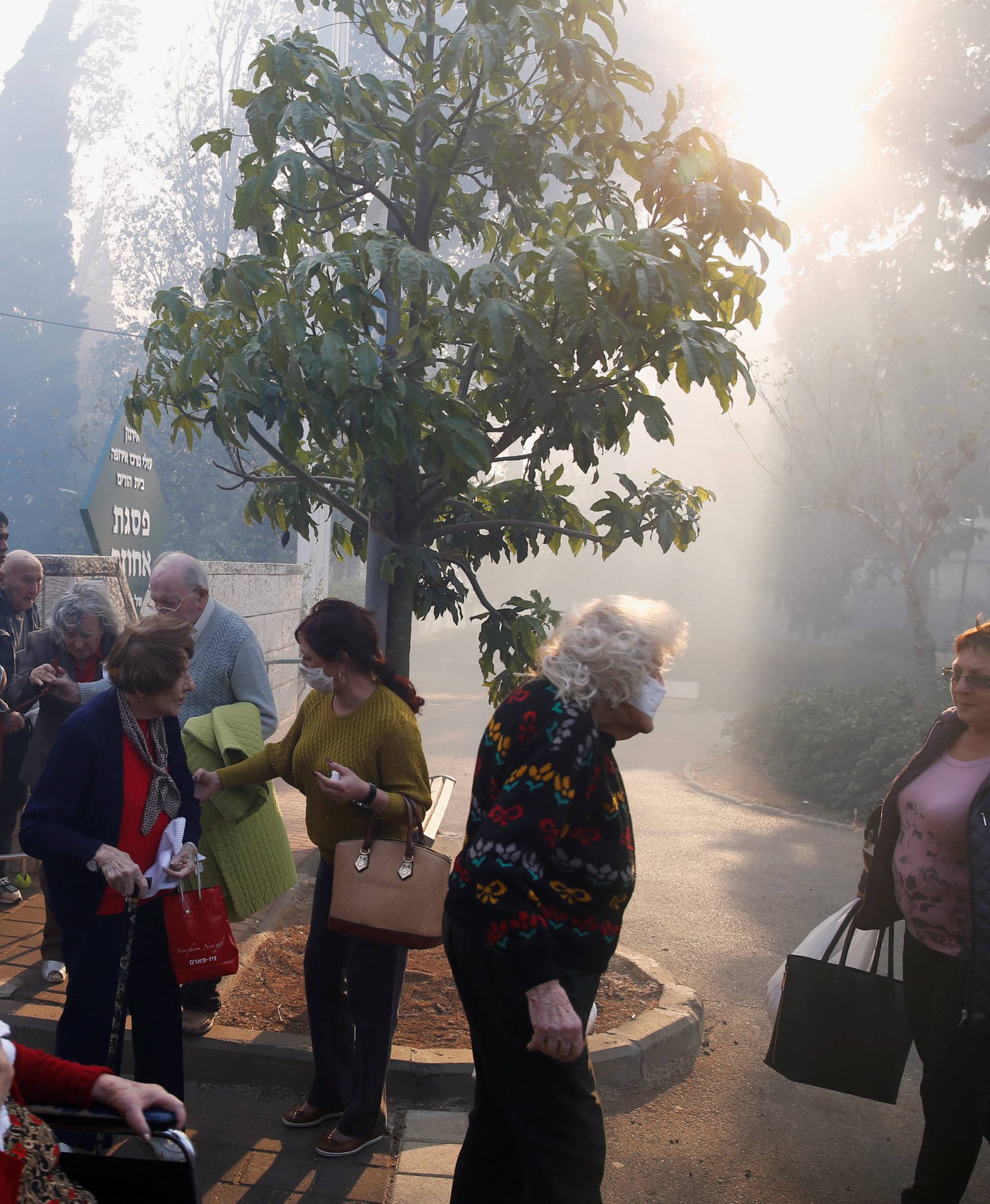 Emergency personnel evacuate elderly people as a wildfire rages in the northern city of Haifa, Israel