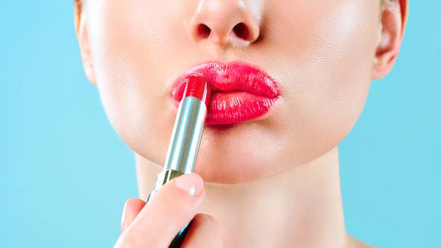 Beautiful woman paints lips with lipstick. Beautiful woman face. Makeup detail. Beauty girl with perfect skin. Red lips and health skin. The concept of beauty, glamor and passion