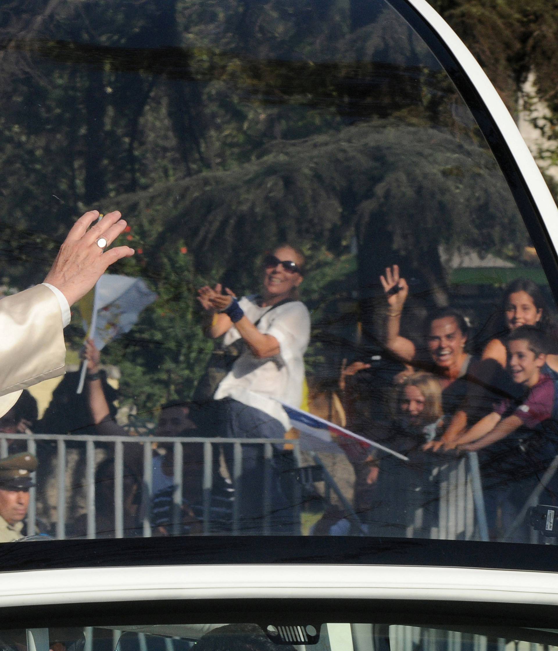 Pope Francis waves while driving through Santiago