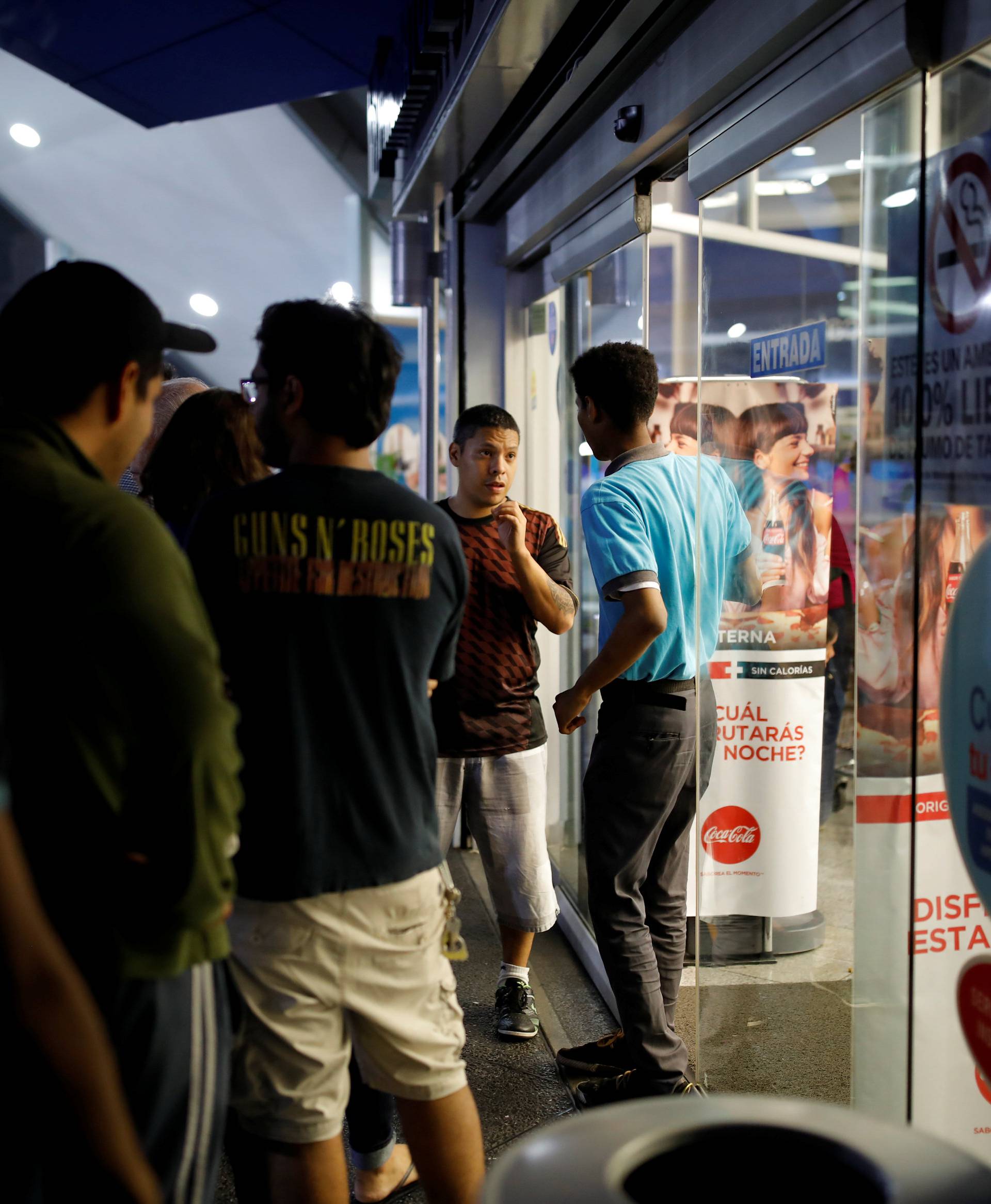 People queue outside a pharmacy to try to buy goods during a blackout in Caracas