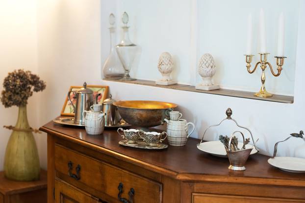 Interior detail with antique cabinet and exquisite ceramic, glass and metal dishes - selective focus