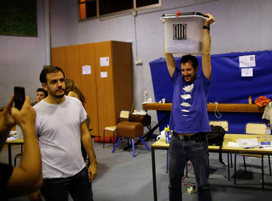 Poll workers celebrate after polls close at a polling station for the banned independence referendum in Barcelona