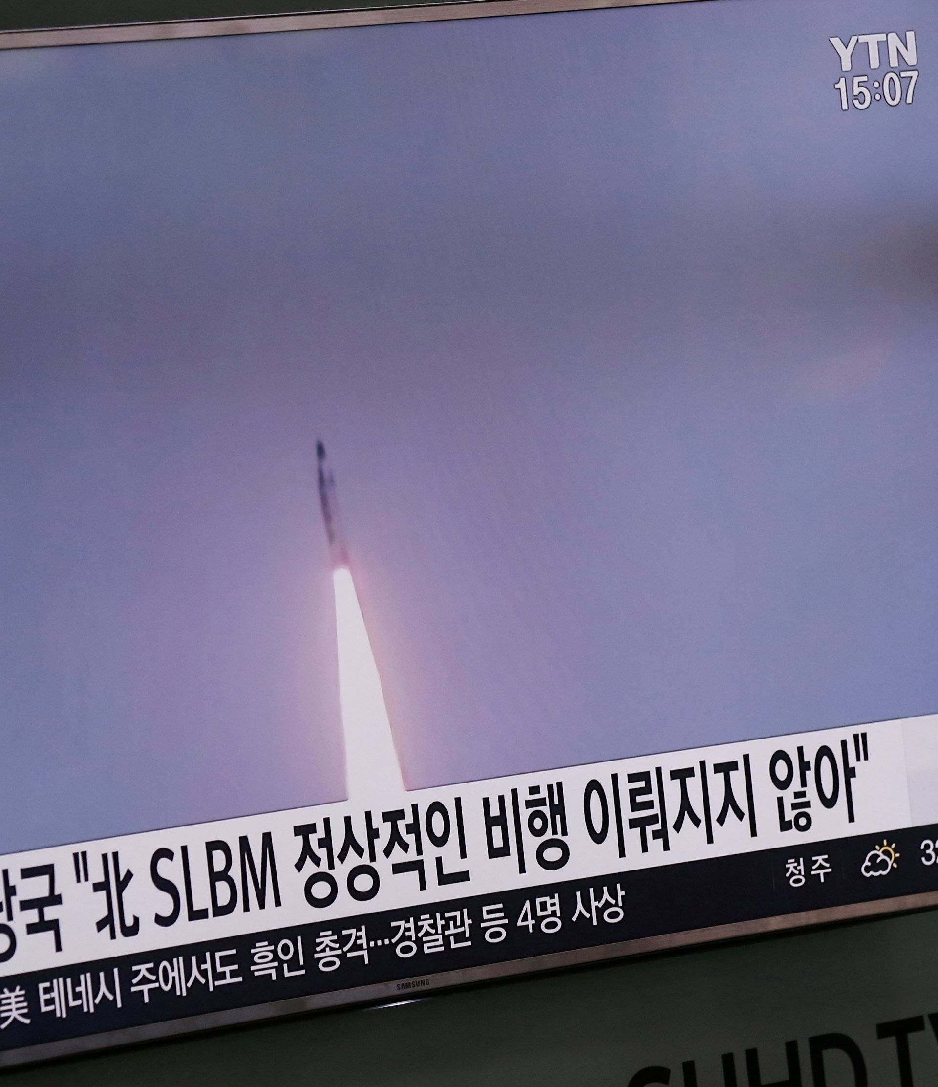 A passenger walks past a TV screen at a railway station in Seoul, South Korea, broadcasting a news report on North Korea's submarine-launched ballistic missile fired from North Korea's east coast port of Sinpo