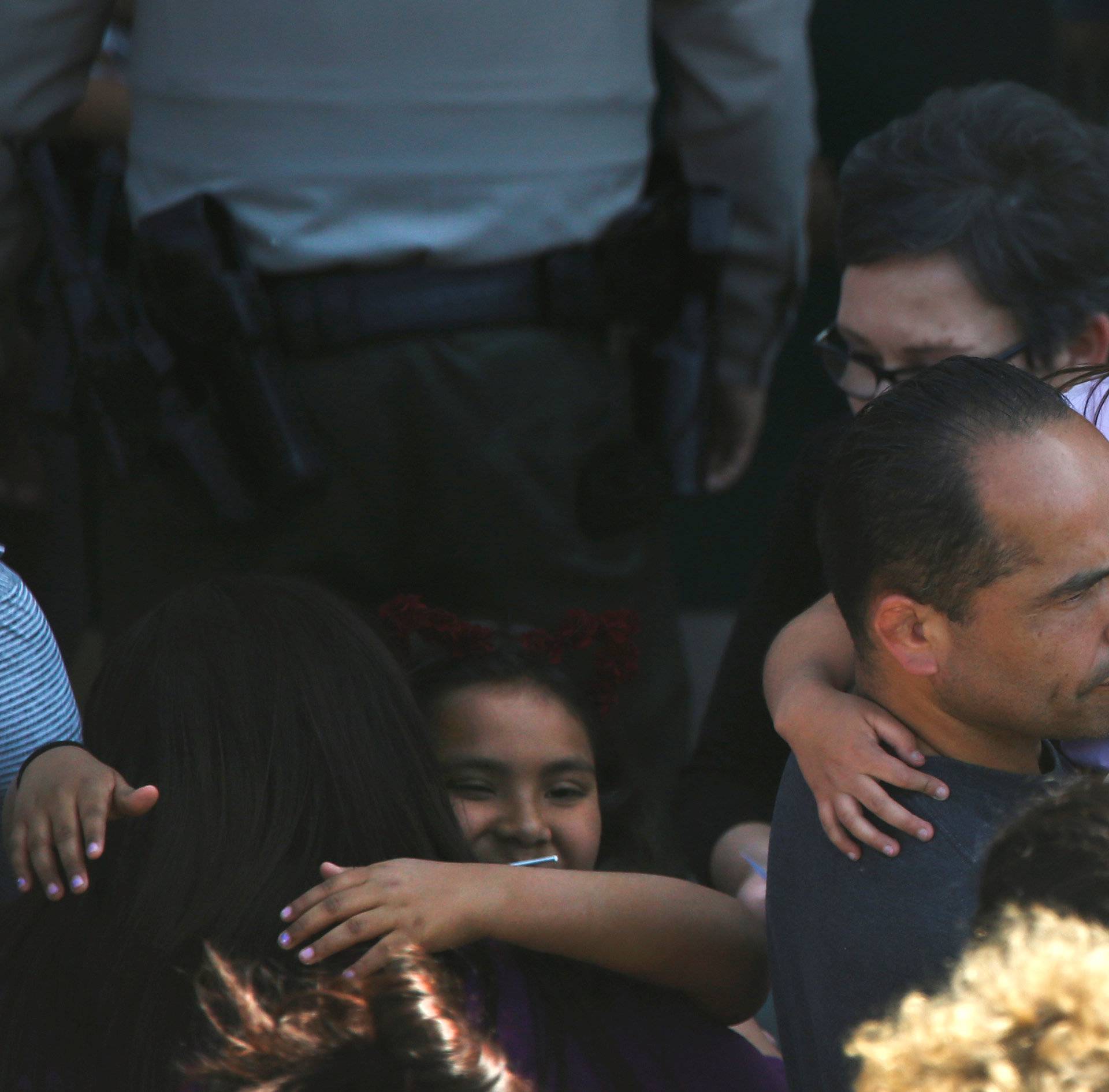 A student who was evacuated after a shooting at North Park Elementary School is embraced after groups of them were reunited with parents waiting at a high school in San Bernardino