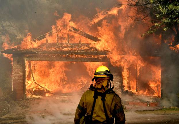 Firefighters battle to save one of many homes burning in an early-morning Creek Fire that broke out in the Kagel Canyon area in the San Fernando Valley north of Los Angeles