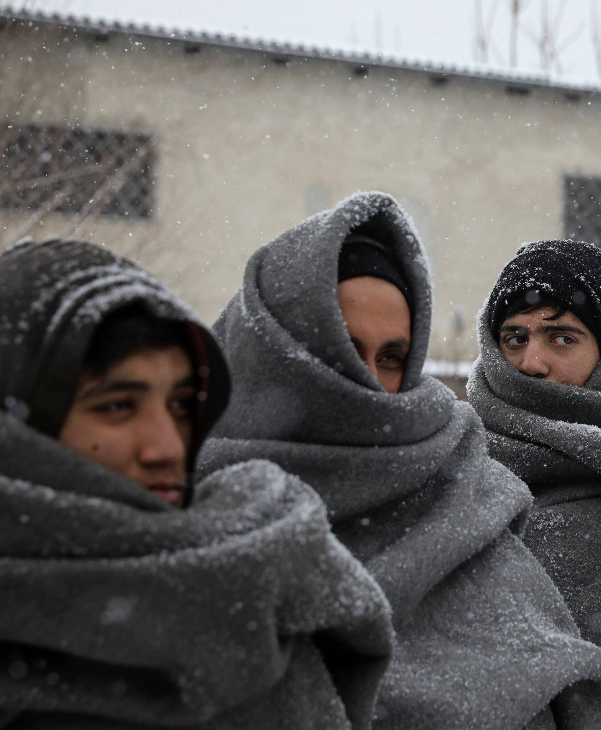 Migrants wait in line to receive free food during a snowfall outside a derelict customs warehouse in Belgrade