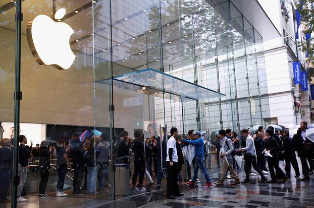 Apple Store staff greets customers who have been waiting in line to purchase Apple