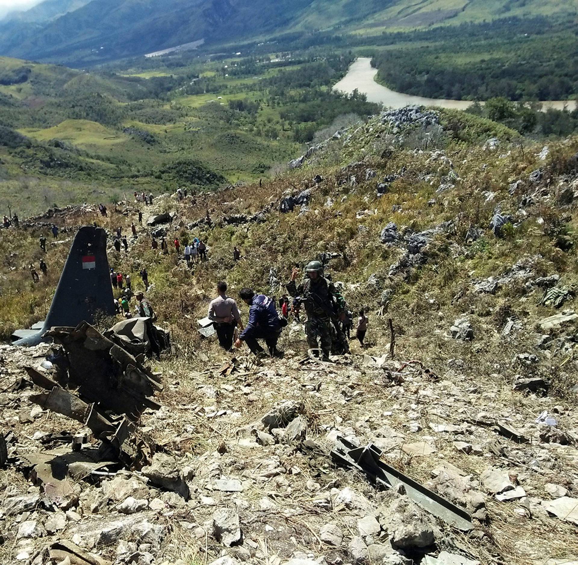 Rescue teams and locals are seen at the crash site of Indonesian air force transport plane which killed all 13 people board, on Mount Lisuwa, near Wamena in the remote region of Papua, Indonesia