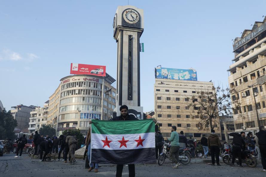 A man holds a Syrian opposition flag near the clock tower in Homs