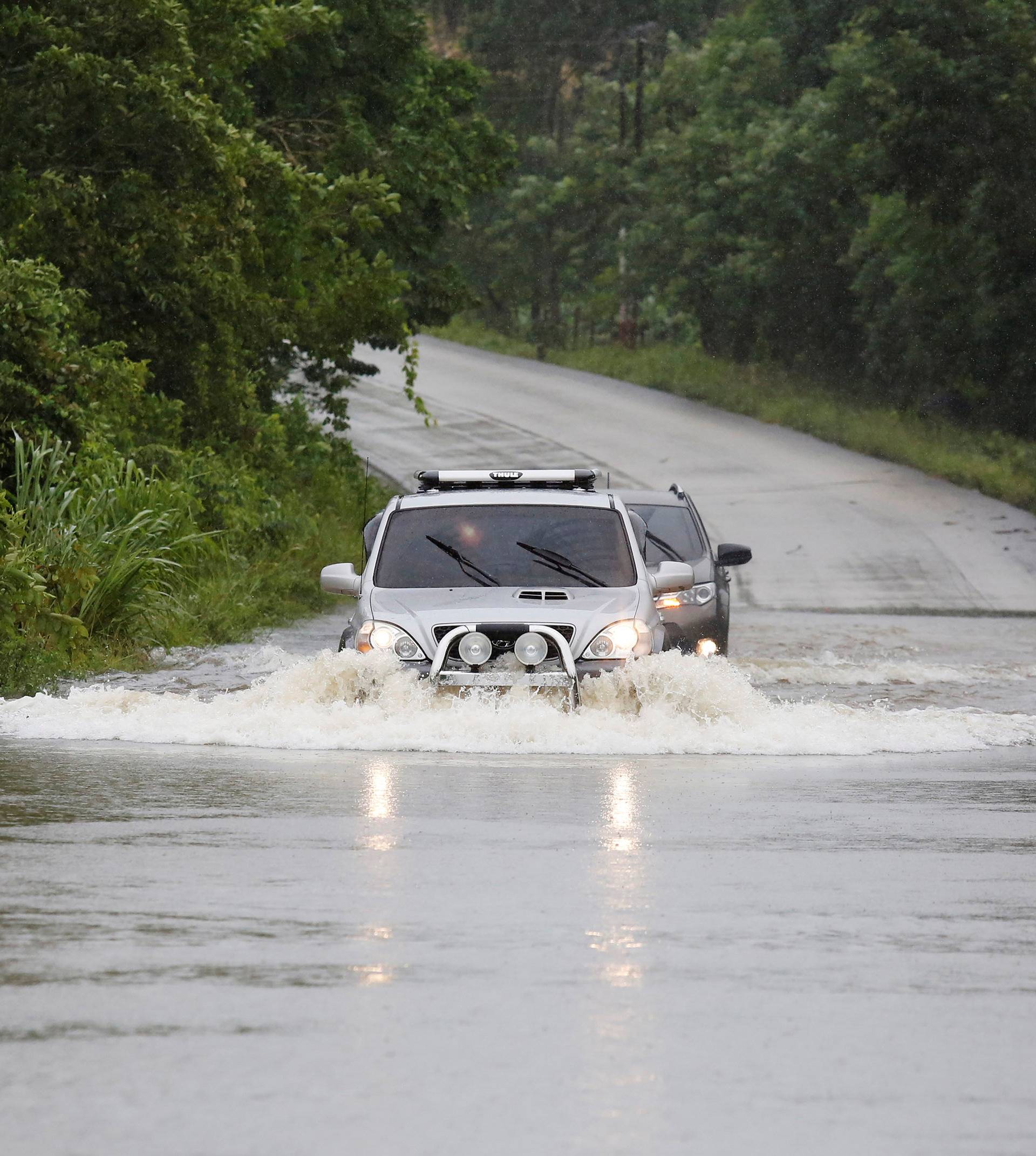 Vehicles travel through a flooded road in the aftermath of Hurricane Earl, in Peten