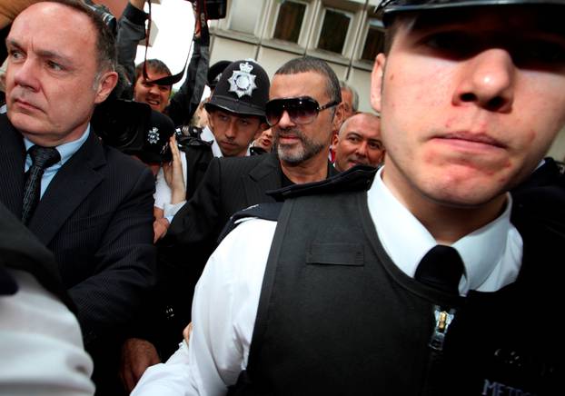 FILE PHOTO: British singer George Michael is escorted out of Highbury Corner Magistrates Court in London,