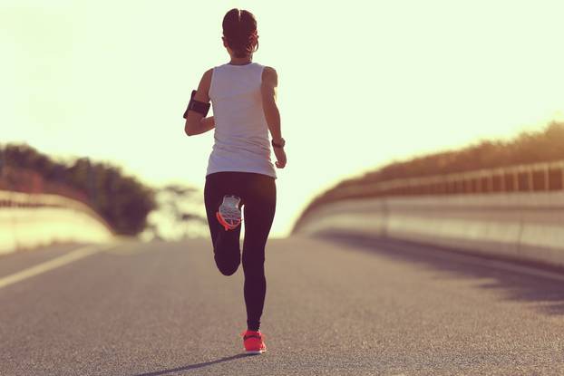 young fitness woman runner running on sunrise road