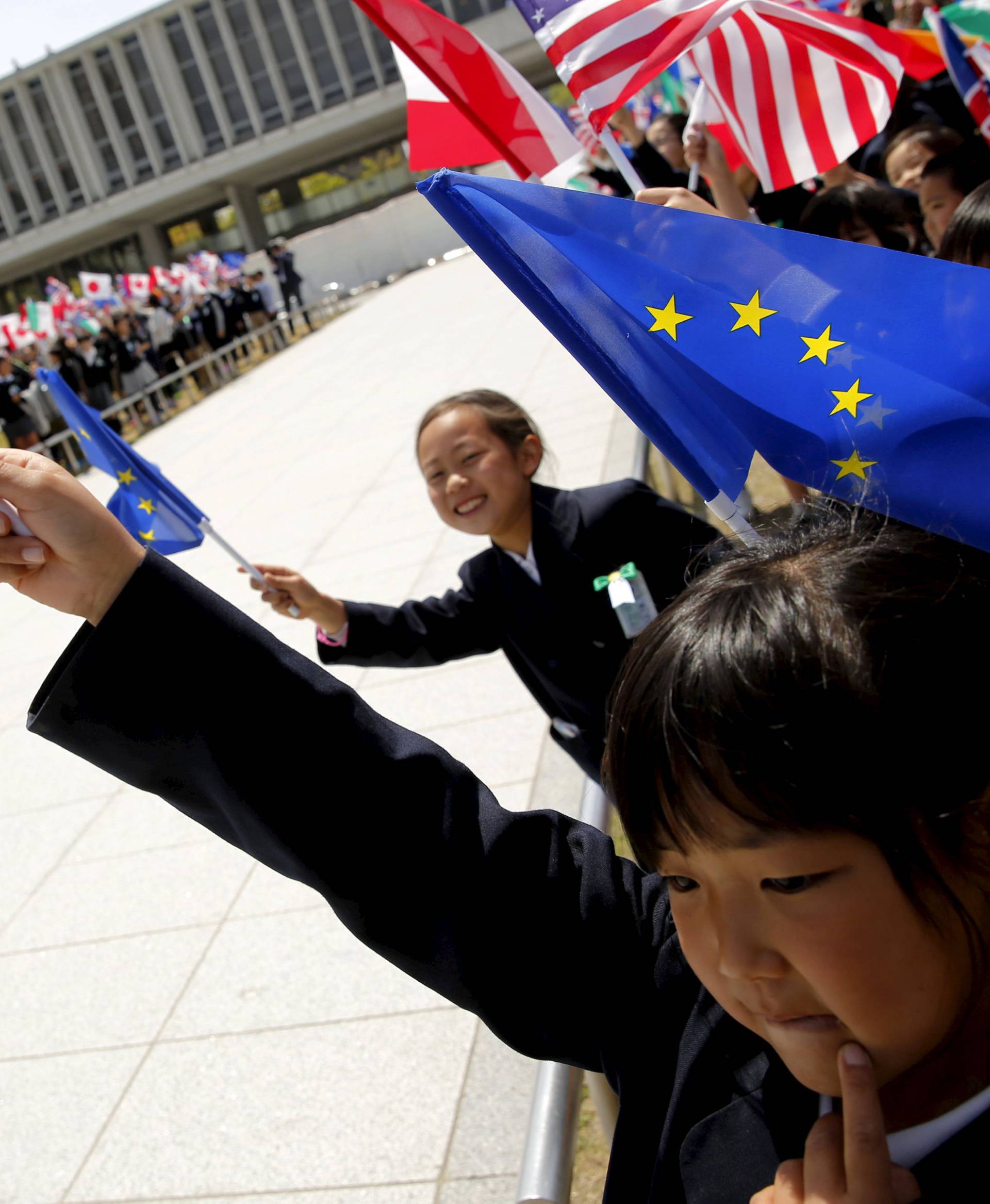 Children hold flags from G7 countries, including a little girl with a U.S. flag, in the wind as the foreign ministers visit Hiroshima Peace Memorial Park and Museum in Hiroshima, Japan