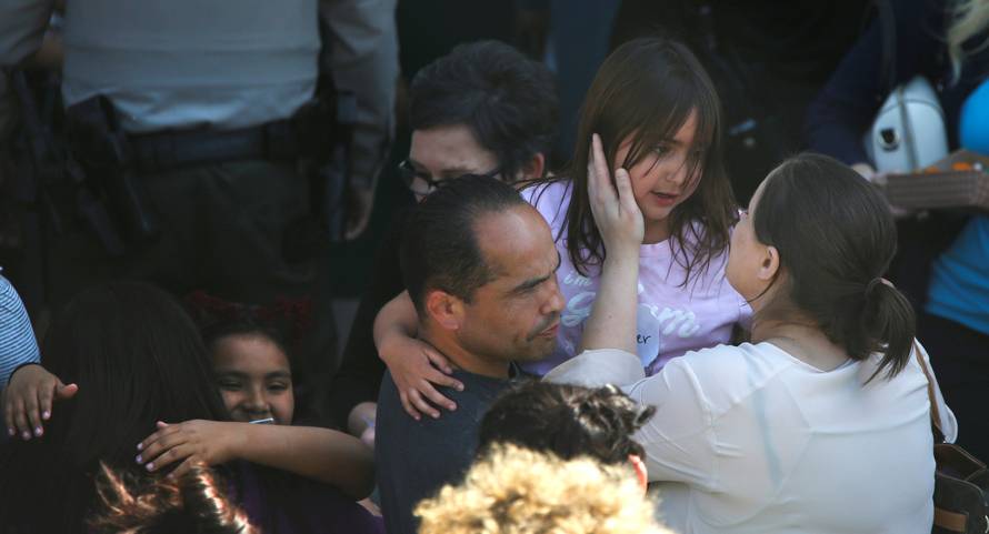 A student who was evacuated after a shooting at North Park Elementary School is embraced after groups of them were reunited with parents waiting at a high school in San Bernardino