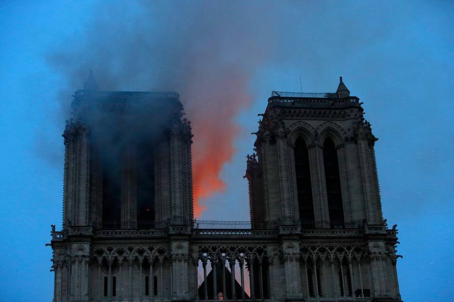 Smoke and flames fill the sky as a fire burns at the Notre Dame Cathedral during the visit by French President Emmanuel Macron (not pictured) in Paris
