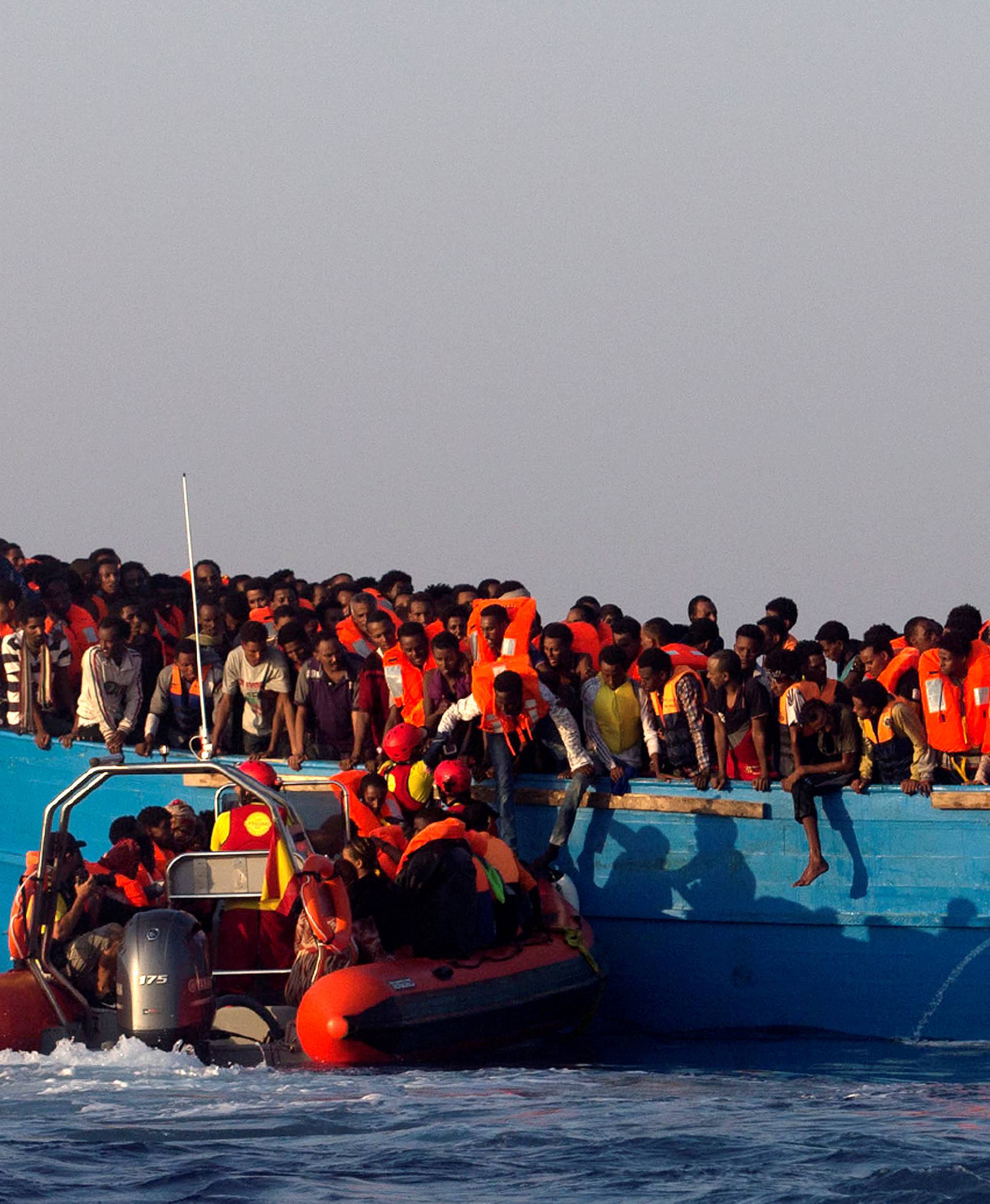 A rescue boat of the Spanish NGO Proactiva approaches an overcrowded wooden vessel with migrants from Eritrea, off the Libyan coast in Mediterranean Sea