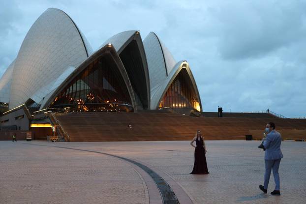 Woman poses for a photo in front of the Sydney Opera House on New Year