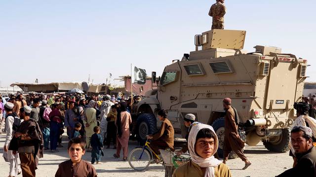 A Pakistan's Army soldier stands guard on a vehicle as people gather and wait to cross at the Friendship Gate crossing point in the Pakistan-Afghanistan border town of Chaman