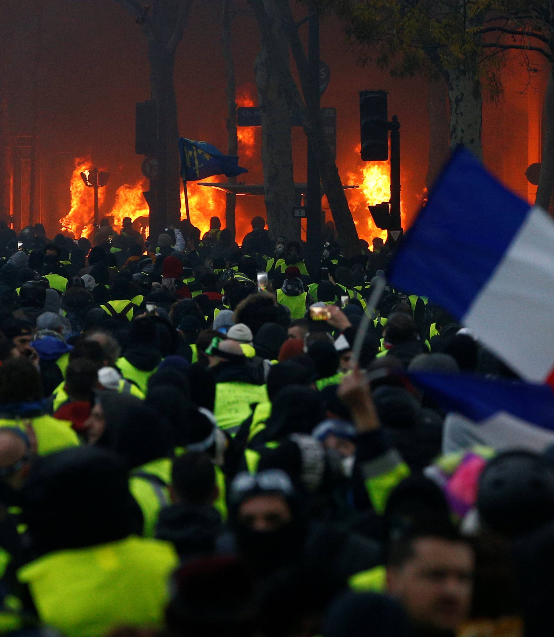A French flag is held by protesters wearing yellow vests, a symbol of a drivers' protest against higher diesel taxes, who demonstrate near the Place de l'Etoile in Paris