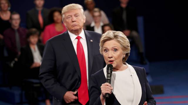 Republican U.S. presidential nominee Trump listens as Democratic nominee Clinton answers a question from the audience during their presidential town hall debate in St. Louis