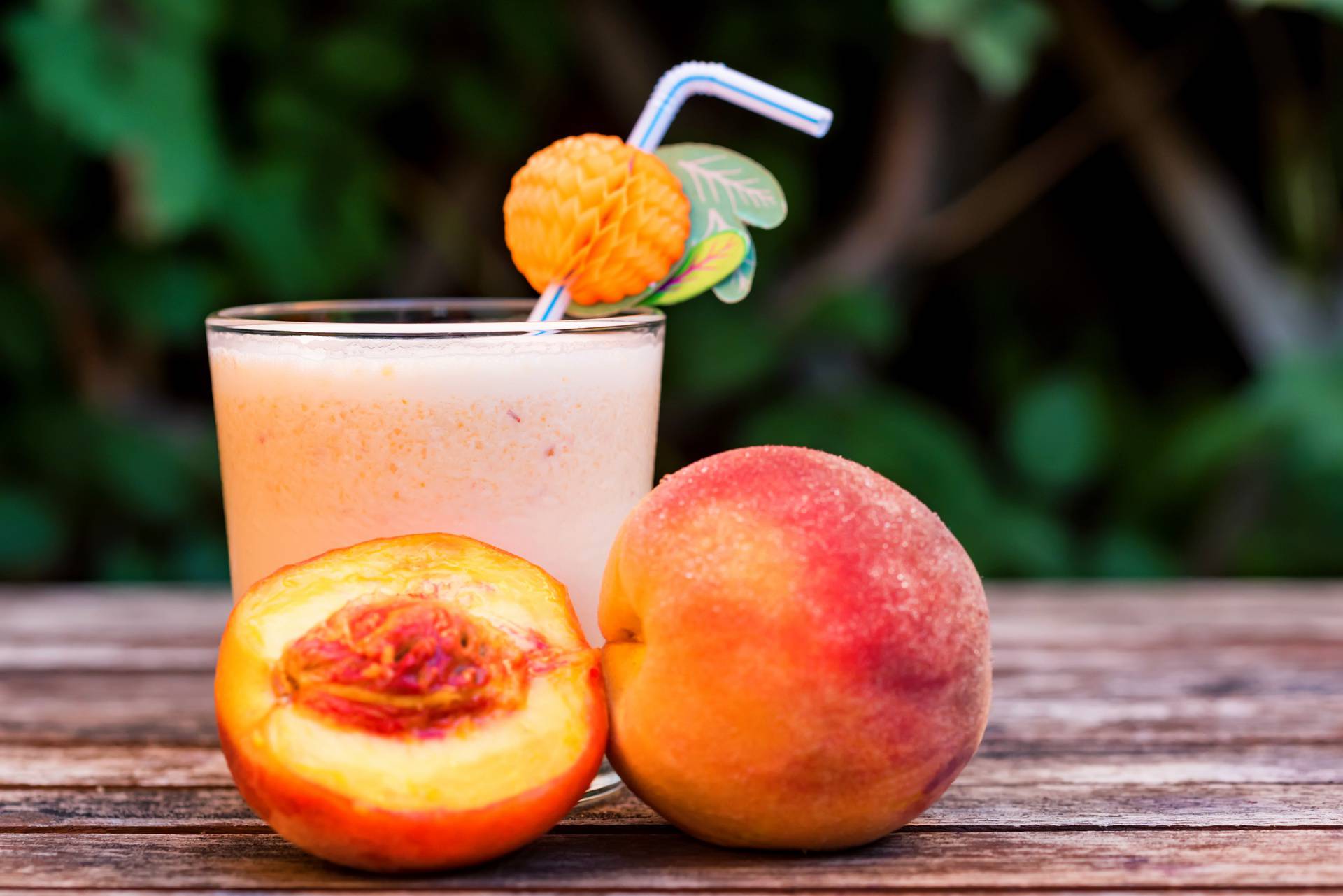 Glass of peach yoghurt and peaches on wooden table